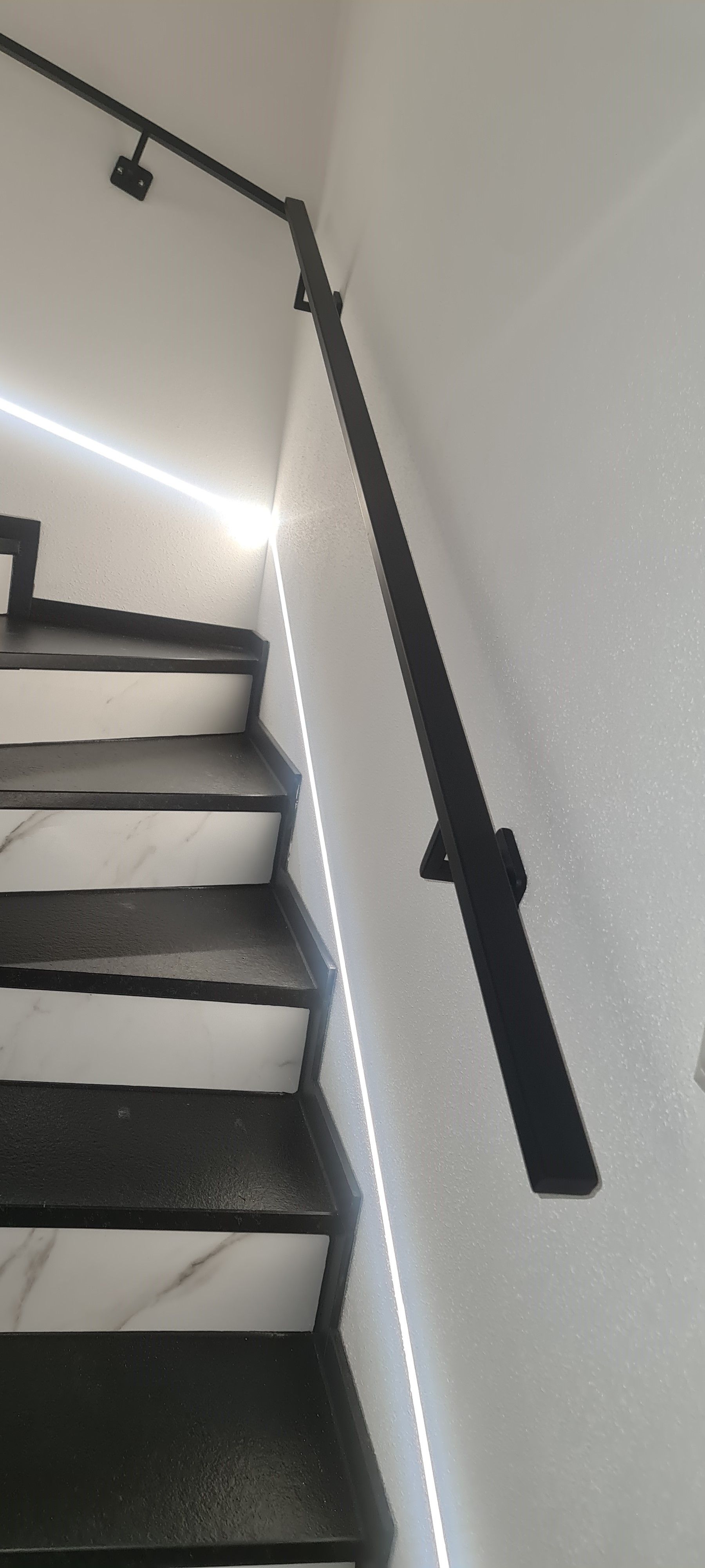 Handlauf mit LED-Beleuchtung Eleganter anthrazitfarbener Handlauf mit integrierter LED-Beleuchtung im Treppenhaus